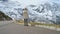 Beautiful girl traveler walks along Majestic Grossglockner Mountain Road in Austria, snow covered sharp peaks of the