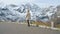 Beautiful girl traveler walks along Majestic Grossglockner Mountain Road in Austria, snow covered sharp peaks of the