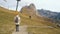 Beautiful girl traveler walks to the famous Mount Seceda in the Dolomites. Mountain trail in Alps mountains in autumn or