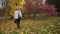 Beautiful girl walks in colourful autumn park, puts on hat and looks aside