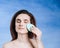 Beautiful girl washes face makeup with a sponge. Eyes closed,  on a blue background