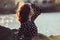 Beautiful girl wearing black polka dots dress enjoy summer sun on ocean beach at sunset time.