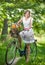 Beautiful girl wearing a nice white dress having fun in park with bicycle. Healthy outdoor lifestyle concept. Vintage scenery