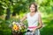 Beautiful girl wearing a nice white dress having fun in park with bicycle. Healthy outdoor lifestyle concept. Vintage scenery