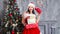 Beautiful girl wearing santa claus clothes . Smiling woman with big and small gift. Women on dress and santa`s hat.