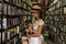 Beautiful girl wearing stylish outfit looking for interesting book in the vintage bookstore