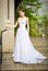 Beautiful girl wearing white wedding dress posing alone on the chapel stairs