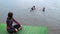 Beautiful girl in a wetsuit is sitting on a pier in the rain