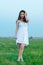 Beautiful girl in white dress walking on spring meadow