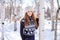 Beautiful girl in white hat stands near the birch in winter