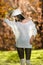 Beautiful girl in white posing in park in autumn day. Beautiful elegant woman with white cap in autumnal park
