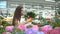 Beautiful girl in a white T-shirt buying green flower plants at flower shop