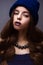 Beautiful girl in winter knitted hat blue color with a necklace around the neck of pearls. Young model with delicate make-up and