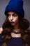 Beautiful girl in winter knitted hat blue color with a necklace around the neck of pearls. Young model with delicate make-up and