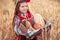 Beautiful girl woman in traditional Bulgarian folklore dress holding wicker basket with homemade breads in wheat field