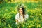 Beautiful girl in wreath of flowers in meadow on sunny day. Portrait of Young beautiful woman wearing a wreath of wild flowers. Y