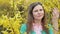 Beautiful girl among yellow blossom spring tree touching and smelling flowers