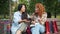 Beautiful girls Asian and Caucasian laughing in park on bench with shopping bags