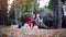 Beautiful girls making selfie on a picnic in autumn park sitting on the fallen leaves near the pumpkin at halloween time