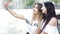 Beautiful girls take a selfie on a smartphone near the fountain.