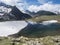 Beautiful glacial lake with springs from melting ice glacier with sharp snow-capped mountain peaks reflecting on water