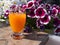 Beautiful  glas of orange juice  on the background of Petunia Violet flowers