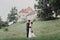 Beautiful gorgeous bride and groom walking in sunny park and kissing. happy wedding couple hugging in green garden at old castle.