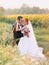 Beautiful gorgeous redhair bride and stylish handsome groom posing in a sunflower sunny field