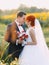 Beautiful gorgeous redhair bride and stylish handsome groom in a sunflower sunny field