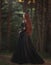 A beautiful gothic princess with pale skin and very long red hair in a black crown and a black long dress walks in a misty fairy-t