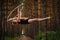 Beautiful and graceful aerial gymnast does exercises on the ring in the forest