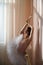 Beautiful graceful ballerina is practicing in the hall against the background of a window. Slender woman in tutu and