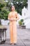 A beautiful, graceful Thai woman in Thai dress adorned with valuable jewelry stands in a beautiful ancient Thai temple