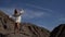 Beautiful graceful woman is posing on rocks in desert in sunny day