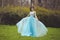 A beautiful graduate girl is spinning in a clearing in a blue dress. Elegant young woman in a beautiful dress in the