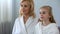 Beautiful grandmother and granddaughter looking at mirror in bathroom, skin care