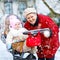 Beautiful grandmother walking with baby girl in pram during snowfall in winter. Happy family. Carefree childhood and