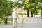 Beautiful granny and her little grandchild walking together in park