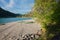 Beautiful gravel beach with rowing boats, lake walchensee bavaria. blooming apple tree in spring