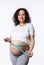 Beautiful gravid pregnant woman measuring her big belly in third trimester with tape, isolated white studio background.