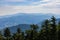 Beautiful green and blue panorama of layers of mountains and trees and some fields seen from top of viewing tower