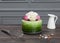 Beautiful green cake decorated with flowers stands on dark wooden board, near corolla and white pitcher