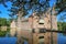 Beautiful green dutch garden park with water moat and reflections of medieval castle wall and tower - Kasteel Heeswijk,