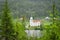 Beautiful green evergreen fir trees flank view of lake, white church and homes