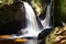 Beautiful green forest landscape with creek and waterfall with slow shutter speed and bright sunlight in the summer