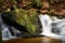 Beautiful green forest landscape with creek and waterfall with slow shutter speed and bright sunlight in the summer