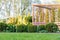 Beautiful green garden with frsesh boxwood bushes, flowers and wood grating summerhouse.Scenic summer gardening background.