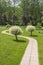 Beautiful green garden with a path going between two Japanese willow trees