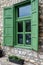 Beautiful green jalousie windows of renovated old building with stone walls
