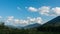 Beautiful green pine forested mountains valley and white clouds floating by the blue sky time lapse at the bright summer day